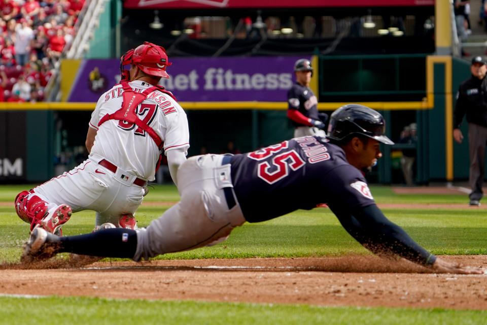 Cleveland Guardians left fielder Oscar Mercado (35) scores as Cincinnati Reds catcher Tyler Stephenson (37) receives the throw in the third inning during a baseball game, Tuesday, April 12, 2022, at Great American Ball Park in Cincinnati, Ohio. 