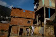 En esta foto del 27 de marzo de 2014, el médico cubano Camilo Rodríguez, derecha, realiza una visita a una casa en el suburbio de Petare, en Caracas, Venezuela. Muchos de los habitantes de Petare han sido atendidos por doctores cubanos en un programa gratuito gracias a un convenio con el gobierno venezolano. (AP Photo/Fernando Llano)