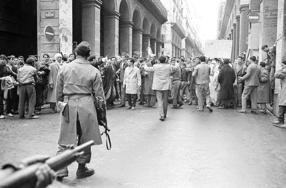 FILE - In this Dec.14, 1960 file photo, armed French soldiers, foreground, face a shouting mob of Algerians at an entrance to the Casbah native quarter in Algiers. French President Emmanuel Macron announced a decision to speed up the declassification of secret documents related to Algeria's seven-year war of independence from 1954 to 1962. (AP Photo, File)