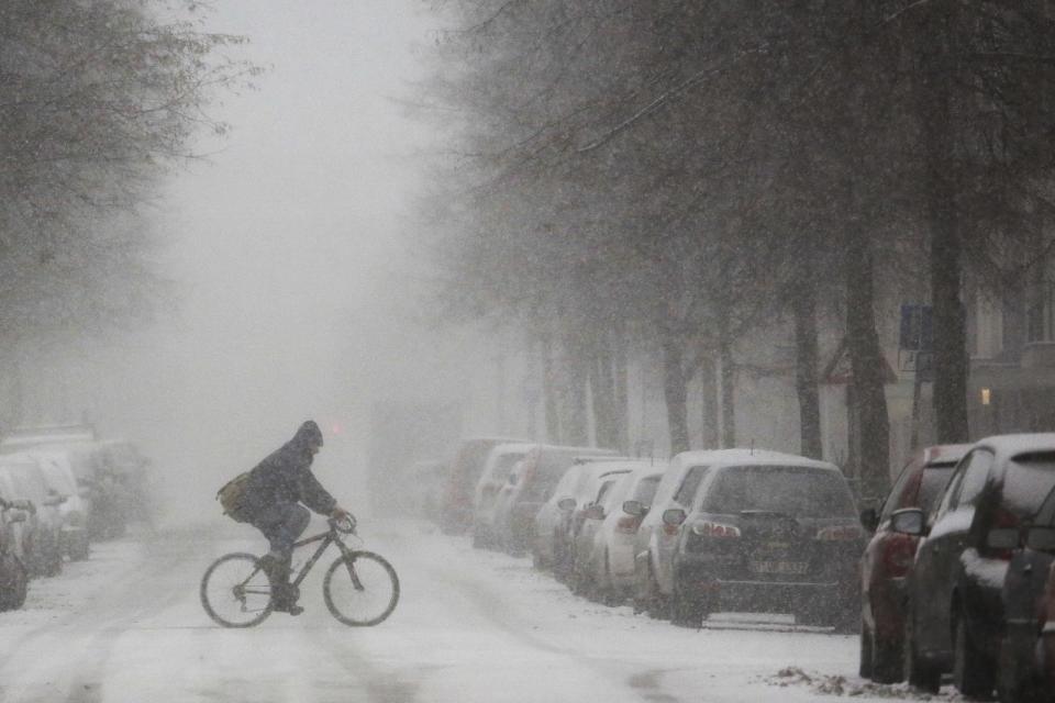 A person rides a bike through heavy snow fall on a day with winter weather in Berlin, Wednesday, Jan. 11, 2017. (AP Photo/Markus Schreiber)