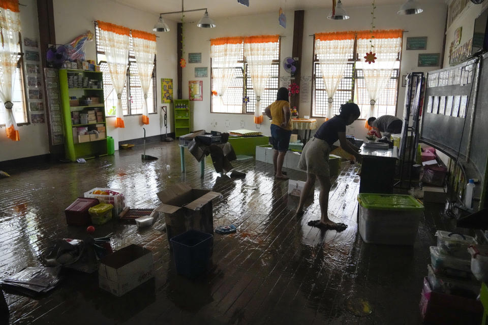 A teacher and her daughter clean out mud inside a classroom from Typhoon Noru in San Miguel town, Bulacan province, Philippines, Monday, Sept. 26, 2022. Typhoon Noru blew out of the northern Philippines on Monday, leaving some people dead, causing floods and power outages and forcing officials to suspend classes and government work in the capital and outlying provinces. (AP Photo/Aaron Favila)