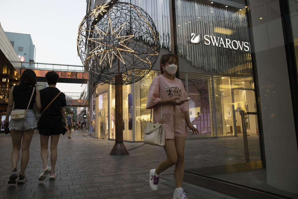 Shoppers pass through an affluent shopping district in Beijing on Tuesday, July 14, 2020. China's economy rebounded from a painful contraction to grow by 3.2% over a year earlier in the latest quarter as anti-virus lockdowns were lifted and factories and stores reopened. (AP Photo/Ng Han Guan)