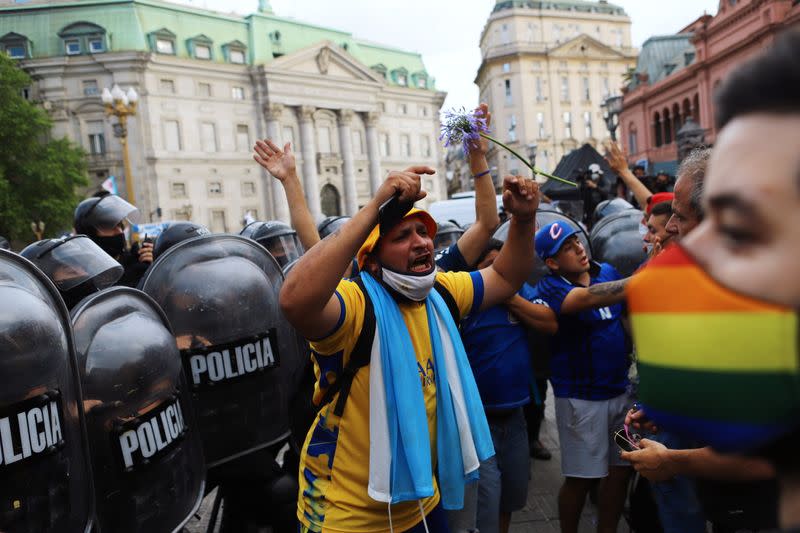 People react while lining up for the wake of soccer legend Diego Maradona at the presidential palace Casa Rosada, in Buenos Aires