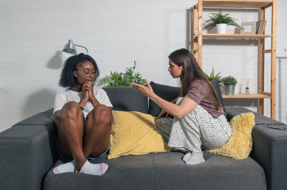 Two people engaged in a serious conversation on a couch, one appears upset