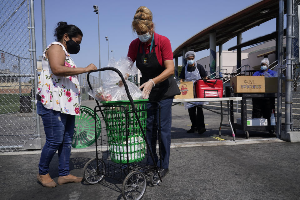 Los Angeles Unified School District food service worker Marisel Dominguez, right, distributes free school meals on Thursday, July 15, 2021, at the Liechty Middle School in Los Angeles. Flush with cash from an unexpected budget surplus, California is launching the nation's largest statewide universal free lunch program. When classrooms open for the fall term, every one of California's 6.2 million public school students will have the option to eat school meals for free, regardless of their family's income. (AP Photo/Damian Dovarganes)