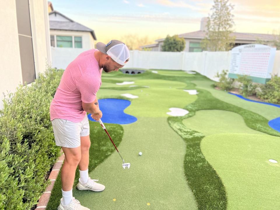 Andrew Augustyniak putts on his version of Augusta National Golf Club in his backyard in Gilbert, Ariz.