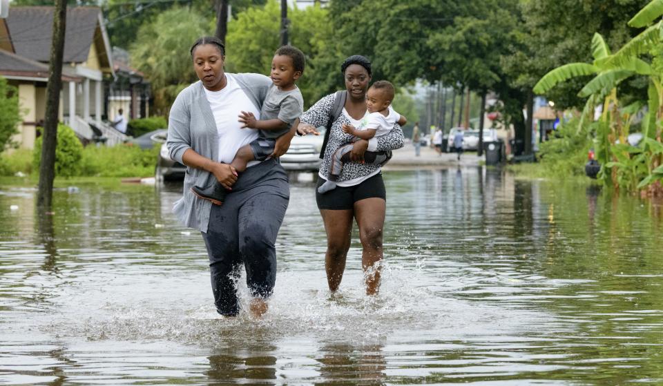 Jalana Furlough carries her son Drew Furlough as Terrian Jones carries Chance Furlough on Belfast Street near Eagle Street in New Orleans after flooding from a tropical wave system in the Gulf Mexico that dumped lots of rain in Wednesday, July 10, 2019. (AP Photo/Matthew Hinton)