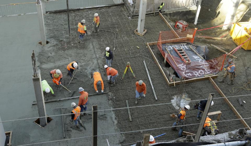 Workers smooth freshly poured cement near a fenced off area at a Seattle construction site, Wednesday, Feb. 12, 2014, where what is believed to be an ice age mammoth tusk was discovered on Tuesday. Work pouring cement at the site was continuing, but workers blocked off the area where the tusk was found. Paleontologists from the University of Washington hope to move the tusk to a museum on campus. (AP Photo/Ted S. Warren)