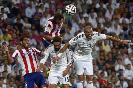 Real Madrid's Pepe (R) and Daniel Carvajal (C, bottom) fight for the ball with Atletico Madrid's Raul Garcia (L) and Diego Godin during their Spanish Super Cup first leg soccer match at the Santiago Bernabeu stadium in Madrid August 19, 2014. REUTERS/Juan Medina