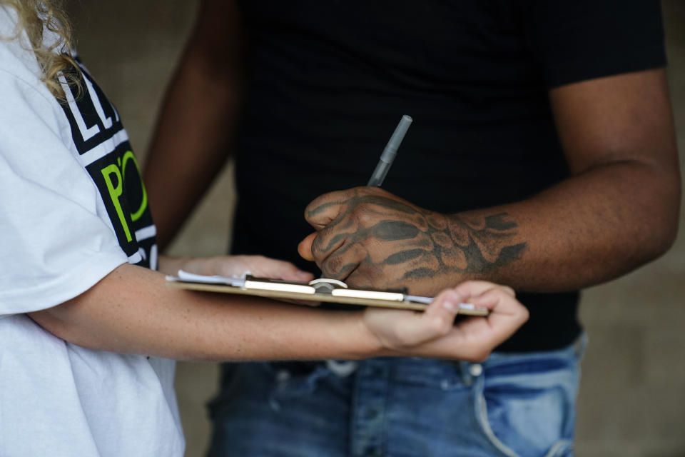 FILE - Canvasser Sienna Giraldi, 26, left, with Stop Cop City Vote Coalition Georgia, talks to an Atlanta resident, Thursday, July 20, 2023, in Atlanta. Georgia activists are furious that Democratic senators haven’t condemned Atlanta officials’ plan to verify every signature on a petition to force a vote on a proposed police and firefighting training center. “Stop Cop City” activists say they’ve gathered more than 100,000 signatures. (AP Photo/Brynn Anderson)