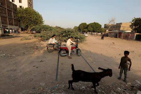 People cross over the tracks of the now disused Karachi Circular Railway line near the abandoned Nazimabad station in Karachi, Pakistan, May 23, 2017. REUTERS/Caren Firouz/Files