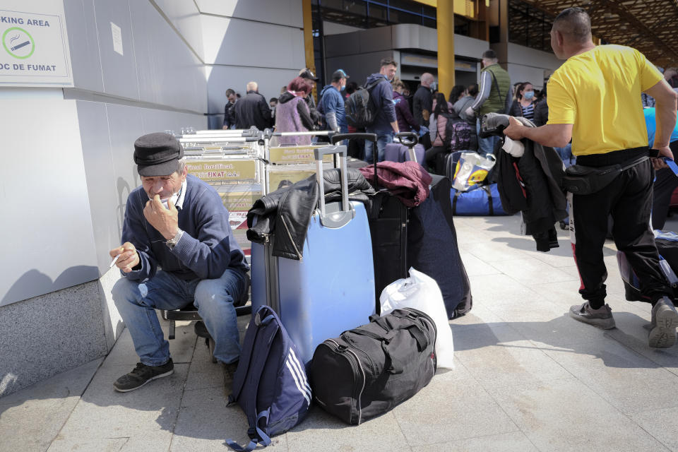 Romanian seasonal workers wait outside the Avram Iancu international airport, in Cluj, central Romania, Thursday, April 9, 2020. More then 1800 workers from across Romania are traveling on 12 flights to Berlin, Baden Bade and Dusseldorf in Germany, most of them to work in asparagus farms. (AP Photo/Raul Stef)