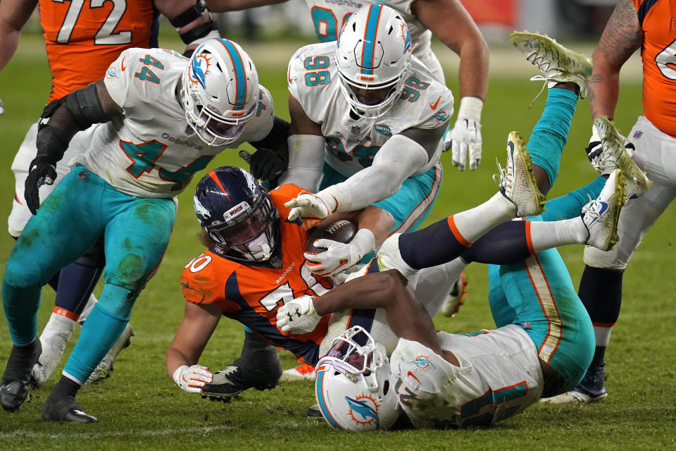 Denver Broncos running back Phillip Lindsay (30) is hit by Miami Dolphins free safety Eric Rowe (21) as outside linebacker Elandon Roberts (44) and defensive tackle Raekwon Davis (98) defend during the second half of an NFL football game, Sunday, Nov. 22, 2020, in Denver. The Broncos won 20-13. (AP Photo/David Zalubowski)