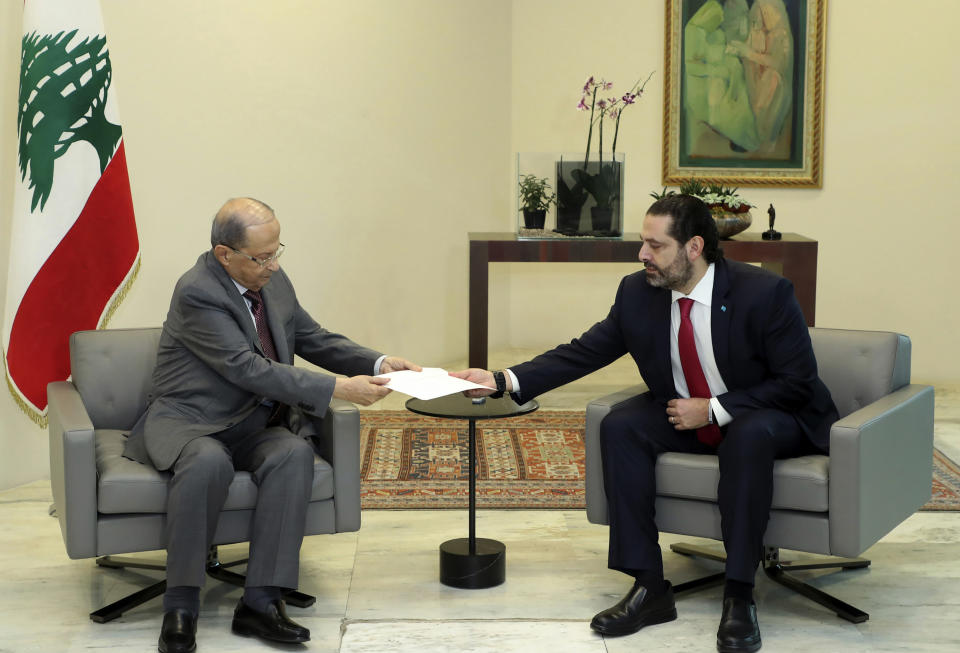 In this photo released by Lebanon's official government photographer Dalati Nohra, Lebanese President Michel Aoun, left, receives a letter of resignation from Prime Minister Saad Hariri, at the presidential palace, in Baabda, east of Beirut, Lebanon, Tuesday, Oct. 29, 2019. Hariri resigned Tuesday, bowing to one of the central demands of anti-government demonstrators shortly after baton-wielding Hezbollah supporters rampaged through the main protest camp in Beirut, torching tents, smashing plastic chairs and chasing away protesters. (Dalati Nohra via AP)