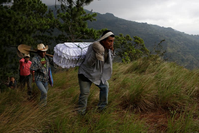 Marvin Roque lleva el ataúd de su difunta sobrina Yesmin Anayeli, una niña de dos años que murió de neumonía relacionada con desnutrición severa, hacia la cima de una colina para su entierro en La Palmilla, Guatemala