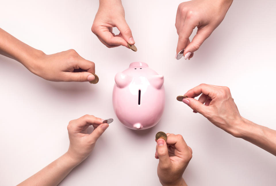 Togetherness concept. People hands throwing coins in piggy bank for crowdfunding, white background