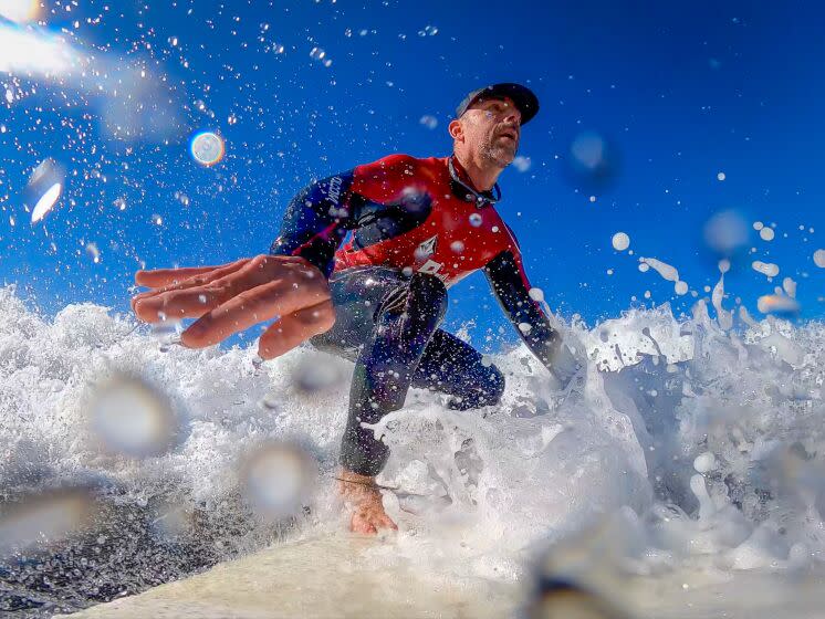 Carlsbad, CA - November 20: With one of his surf coaches, Brooks Venters-not pictured but near by, Pete Gustin, who is known for his popular YouTube web series "Blind Surfer Pete Gustin" and is an award winning voice actor, relies on feeling the energy wave as he surfs at North Ponto Beach in Carlsbad, Sunday, Nov. 20, 2022. (Allen J. Schaben / Los Angeles Times) His motto and slogan is "Find A Way", and encourages his followers that if they want to do something, anything can be achieved by hard work and determination, as he says he has found out in his life. Pete Gustin, aka the Blind Surfer, is legally blind because of a degenerative disease called Stargardt's disease. Stargardt's macular dystrophy (SMD) is inherited from parents who have recessive genetic traits for the disease. Central vision loss tends to start early in life, getting worse as time passes. Unlike a lot of surf content, it's not all exotic travel and getting barreled. His content shows being scared, the struggles of surfing when you can't see what's coming, while having fun. He gets advice and direction from one of his surf coaches Brooks Venters and videography, video editing and support fiance Maggie Carpenter. Because Gustin is so busy during the week as a voice actor in high demand, he only surfs on surfs on weekends with a surf coach. Gustin has navigated his challenges by wearing a hat to narrow his field of vision and sunglasses that him distinguish between the light of the horizon and the darkness of the water. Gustin surfs with a coach, who directs him through set waves and around the lineup and gives him instructions where to paddle to get in position to ride incoming waves. Gustin is riding a surfboard designed and gifted to him by former pro surfer Rob Machado.