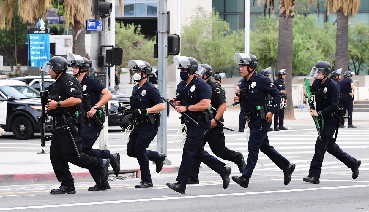 Officers from the Los Angeles Police Department run to formation during a march over the death of George Floyd, an unarmed black man, who died after a police officer kneeled on his neck for several minutes, in front of the Los Angeles City Hall on June 1, 2020 in Los Angeles, California. - The city and county of Los Angeles has extended curfew for a third night following a weekend of looting in southern California by people taking advantage of those protesting the death of George Floyd. (Photo by Frederic J. BROWN / AFP) (Photo by FREDERIC J. BROWN/AFP via Getty Images)