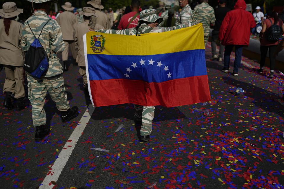 FILE - A Bolivarian Militia member carries a Venezuelan flag during a commemorative march, in Caracas, Venezuela, Feb. 29, 2024. The ruling party is expected to officially name incumbent President Nicolas Maduro, who is seeking his third six-year term, as its candidate in mid-March. (AP Photo/Ariana Cubillos, File)