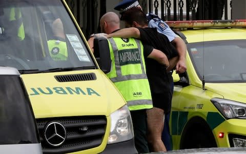 Police and ambulance staff help a wounded man from outside a mosque in central Christchurch, New Zealand, Friday, March 15, 2019 - Credit: Mark Baker/AP