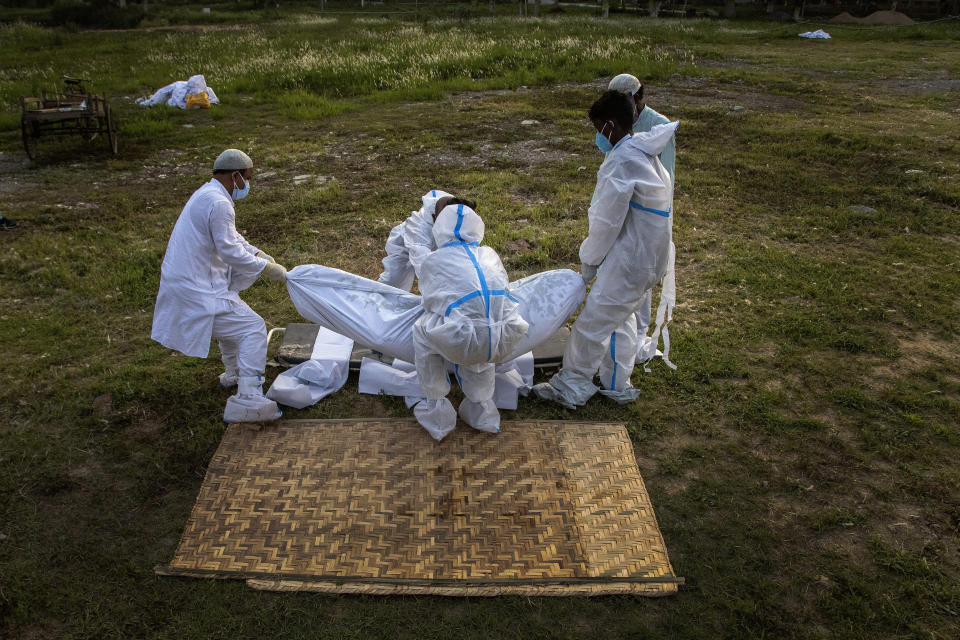 Relatives and municipal workers prepare to bury the body of a person who died of COVID-19 in Gauhati, India, Sunday, April 25, 2021. India’s crematoriums and burial grounds are being overwhelmed by the devastating new surge of infections tearing through the populous country with terrifying speed, depleting the supply of life-saving oxygen to critical levels and leaving patients to die while waiting in line to see doctors. (AP Photo/Anupam Nath)