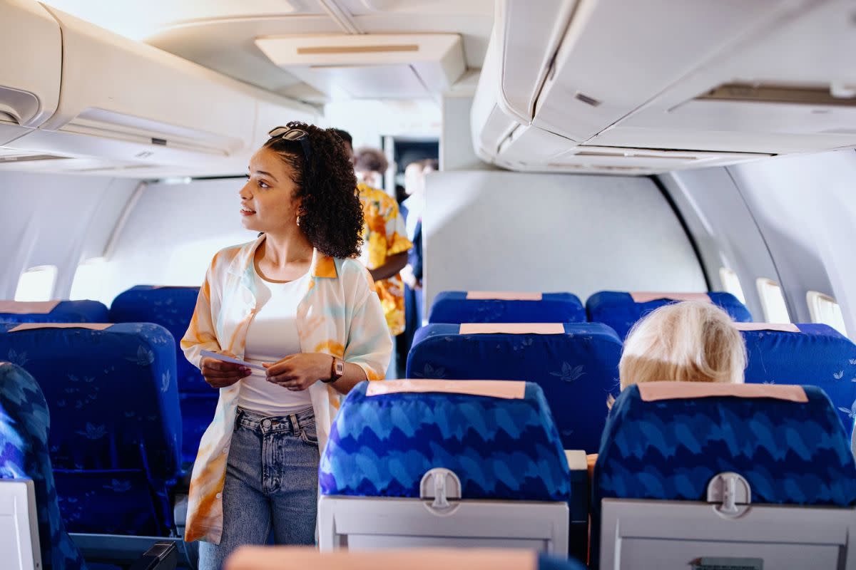 woman looking for seat as she walks down plane aisle