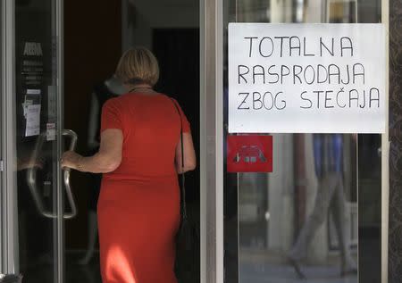 A customer enters an Arena Modna Kuca store in the Adriatic town of Pula July 1, 2014. The sign reads "Complete sale because of bankruptcy." REUTERS/Antonio Bronic