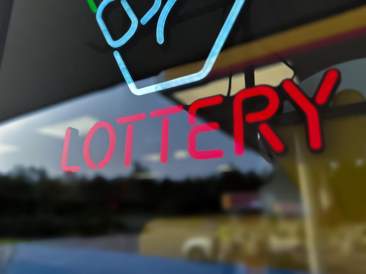 An illuminated lottery sign in a window.