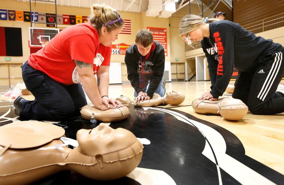 Katie Busch, left, an EMT with American Medical Response, helps River View High sophomore Andrew Miles and Gracie Boyd practice a compression-only technique during a CPR challenge event at the school in Finley in 2019.