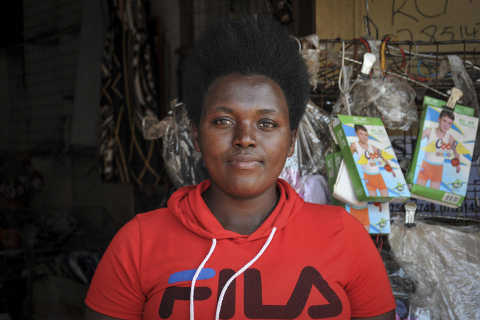 In this photo taken Saturday, June 20, 2020, Grace Twisimire, 25, sits in her once-thriving shop selling clothes and plastic shoes in the capital Kampala, Uganda. The COVID-19 pandemic means that millions of women in Africa and other developing regions could lose years of success in contributing to household incomes, asserting their independence and expanding financial inclusion. (AP Photo/Ronald Kabuubi)