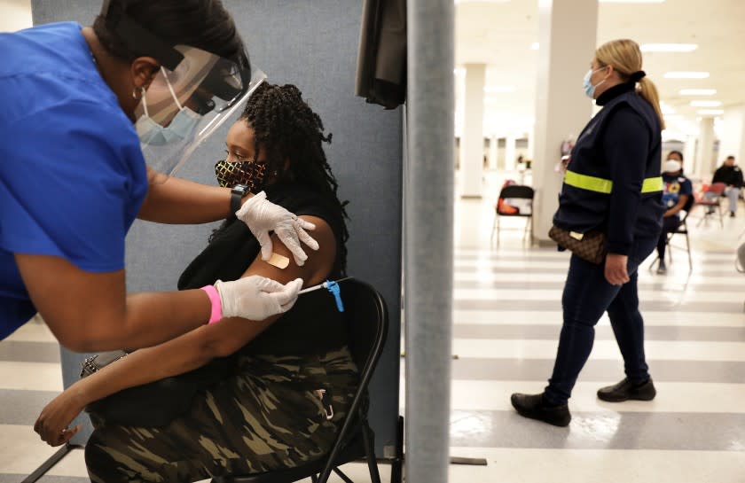 LOS ANGELES-CA-MARCH 11, 2021: A'ja Thrasher, 37, of View Park, gets a one-dose Janssen COVID-19 vaccine by Johnson & Johnson, by nurse LeShay Brown, left, following a media event hosted by The California Department of Public Health as part of the states efforts to increase vaccine acceptance among groups that are less likely to be vaccinated, and highlights California's efforts to equitably and efficiently administer COVID vaccines, at the Baldwin Hills Crenshaw Plaza in Los Angeles on Thursday, March 11, 2021. (Christina House / Los Angeles Times)