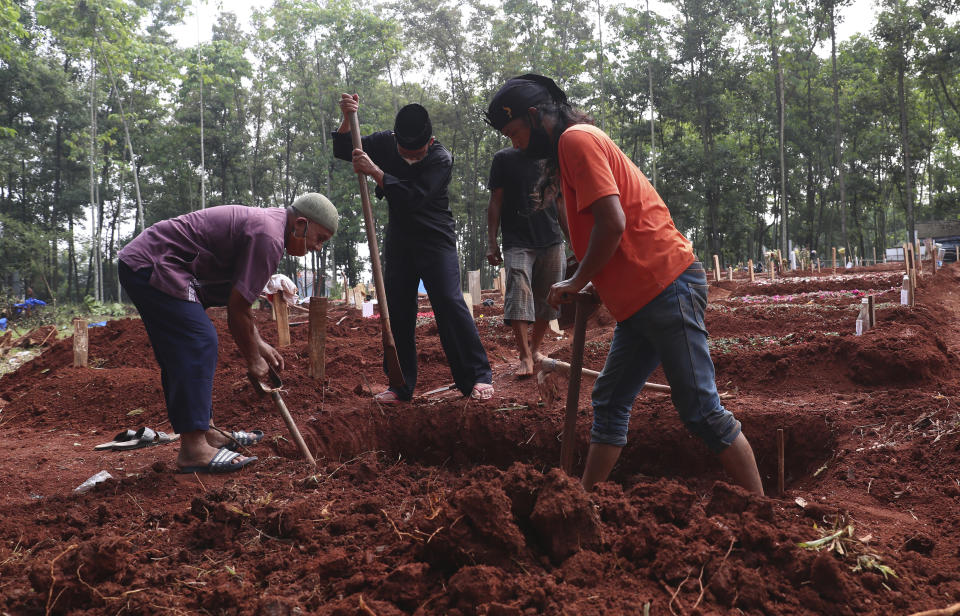 Relatives prepare a grave for a COVID-19 victim at Cipenjo cemetery in Bogor, West Java, Indonesia on July 14, 2021. With the numbers of death increasing from the latest virus surge in Indonesia which has crippled the healthcare system in Java and Bali, relatives and residents decided to volunteer to dig graves using their own hoes and shovels to help exhausting gravediggers. (AP Photo/Achmad Ibrahim)