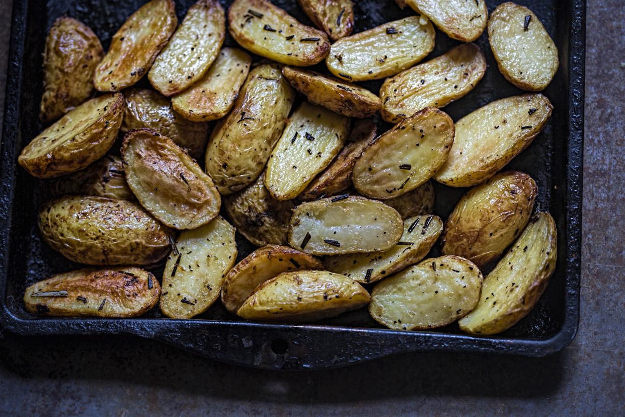 Oven roasted potatoes with herbs on an oven pan on a stone table