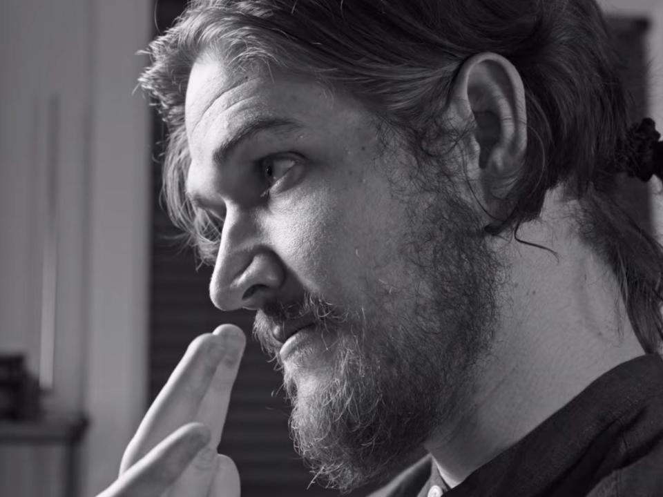 A black and white image of a man (Bo Burnham) holding up the "OK" sign with one hand.