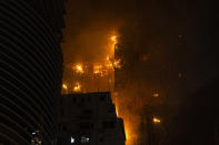 A fire burns at a construction site in Hong Kong, Friday, March 3, 2023. Hong Kong firefighters are battling the blaze that broke out at a construction site in the city's popular shopping district. (AP Photo/Louise Delmotte)