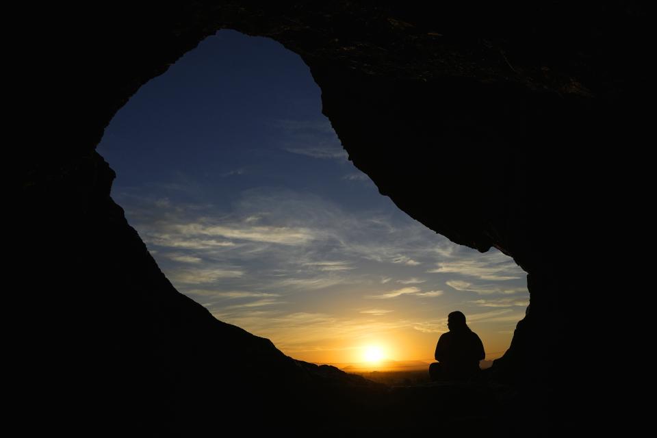 FILE - A hiker pauses at the Hole-in-the-Rock in Papago Park at sunrise July 17, 2023, in Phoenix. (AP Photo/Ross D. Franklin, File)