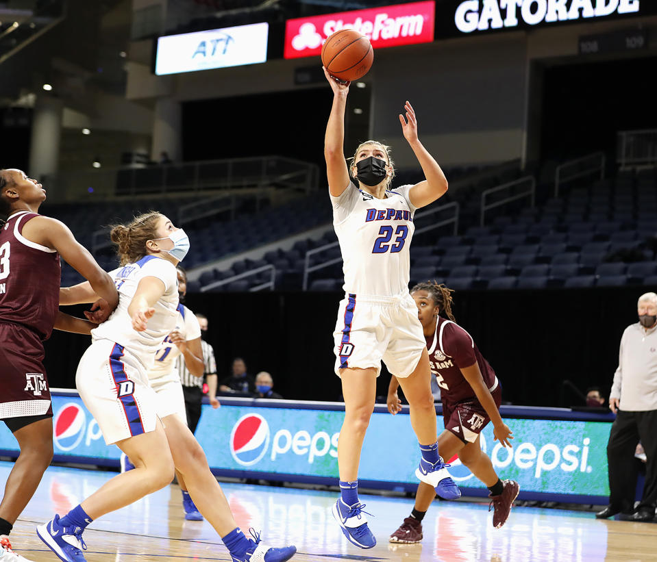 This photo provided by DePaul Athletics shows DePaul's Dee Bekelja (23) shooting during a women's NCAA college basketball game against Texas A&M on Saturday, Nov. 28, 2020, in Chicago. It's a common sight to see players and coaches wear masks on the sideline so far this season during college basketball games to help prevent the spread of the coronavirus. The DePaul and Creighton women's basketball teams are among a few squads that have taken it a step further with their players wearing the masks while they are on the court playing. (Steve Woltmann/DePaul Athletics via AP)