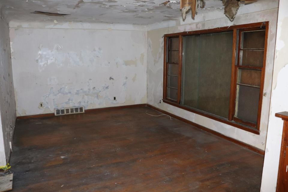 An abandoned living room at Detroit Land Bank Authority with boarded up window.