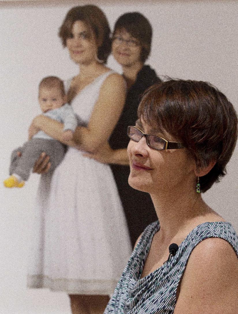 Anna Koopman poses next to a family portrait of her and her partner, Hanne Harbison and their son Amon, Thursday, March 29, 2012 at the Civil Rights Institute in Birmingham, Ala. A show of photographs of lesbian families by Carolyn Sherer will be on display at the institute through June. (AP Photo/Dave Martin)