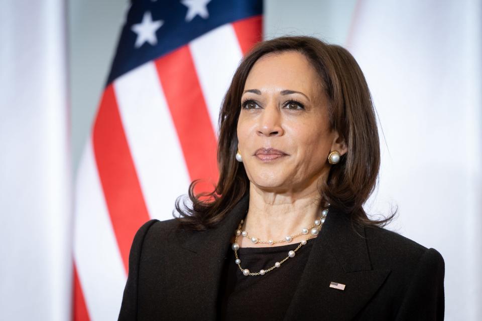 Kamala Harris stands in front of an American flag during a visit to Poland.