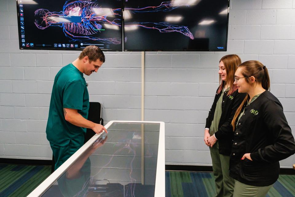 Lucas Grove demonstrates the capabilities of an Anatomgage Table – a specialized medical device designed to enhance medical teaching and learning capabilities at Buckeye Career Center in New Philadelphia. Among other things, the table allows a mock autopsy to be performed three-dimensionally without the use of a cadaver. Looking on are BCC students Brooklyn Hall and Dawson Harvey, both of Newcomerstown High School.