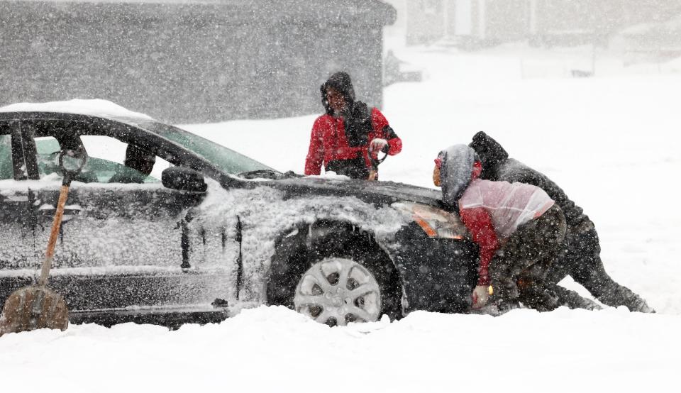 People help a driver push her vehicle out of the snow on Elliot Street in Brockton during a historic nor'easter with blizzard-like conditions on Saturday, Jan. 29, 2022.