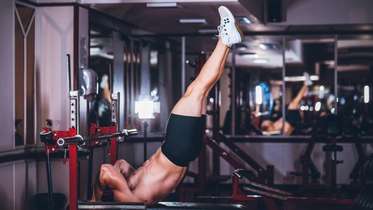  Man performing dragon flags on a weight bench. 