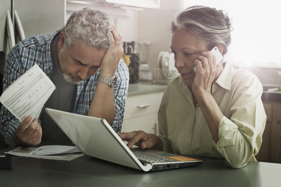 Stressed Hispanic couple paying bills on laptop