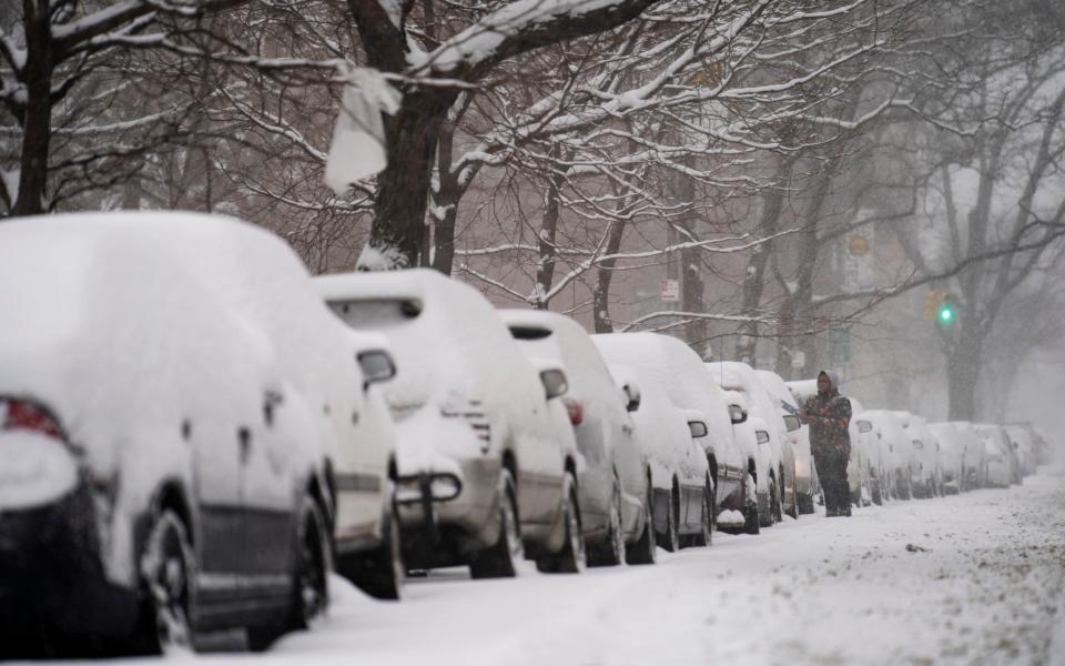 A motorist clears his car of snow in Brooklyn, New York City - John Minchillo /AP