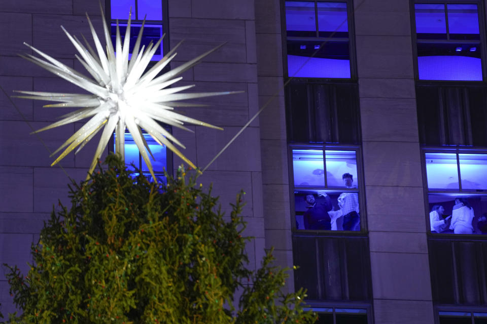 People look out the windows of a building in Rockefeller Center, near the top of a Christmas tree, in New York, Wednesday, Nov. 29, 2023. (AP Photo/Seth Wenig)