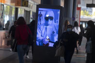 People pass by a poster thanking medical workers at a bus station in Madrid, Spain, Wednesday, Oct. 7, 2020. Spain has become the first western Europe to accumulate more than 1 million confirmed infections as the country of 47 million inhabitants struggles to contain a resurgence of the coronavirus. (AP Photo/Paul White)