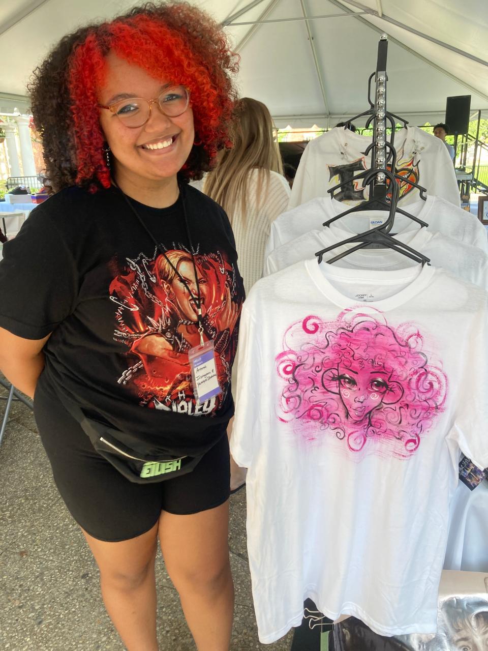 Arieanah Lopes, 15, entering 10th grade, stands next to some of the original T-shirts she designed and had for sale at the Dream Makers Market on Thursday, July 14.