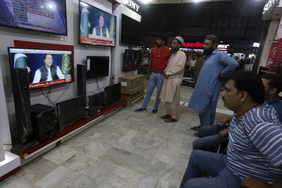 People watches news channels broadcast a live address to the nation by Pakistan's Prime Minister Imran Khan at a shop, in Karachi, Pakistan, Thursday, March 31, 2022. Pakistan's embattled Prime Minister Khan remained defiant on Thursday, telling the nation that he will not resign even as he faces a no-confidence vote in parliament and the country's opposition says it has the numbers to push him out. (AP Photo/Fareed Khan)