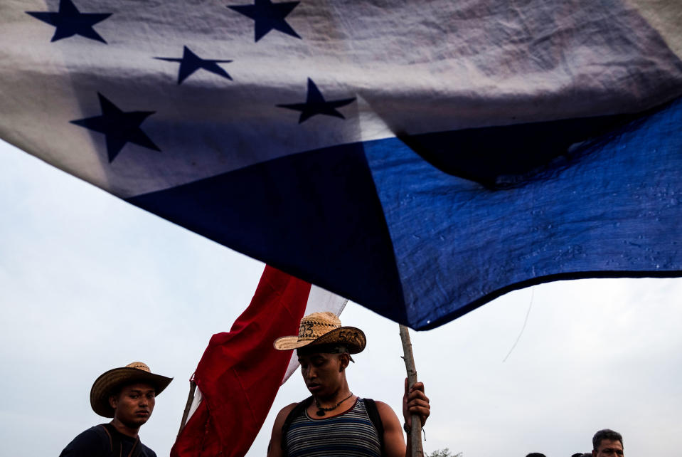 <p>Honduran migrants taking part in a caravan heading to the U.S., carry an Honduran flag as they leave Arriaga on their way to San Pedro Tapanatepec, southern Mexico, on Oct. 27, 2018.(Photo: Guillermo Arias/AFP/Getty Images) </p>